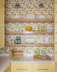Yellow kitchen with open shelving oyster  and yellow wallpaper with pastel blue and brass wall sconces by sazerac stitches