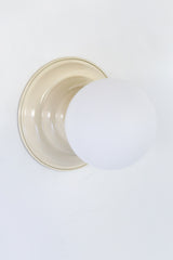 Neutral Cream flushmount ceiling light or wall sconce with a frosted white globe.  Stepping back into a bygone era with a touch of modern minimalism, the Abeille Sconce or Flushmount is an artistic blend of form and function. This wall sconce doubles as a flushmount ceiling light, making it a versatile lighting solution for any space. Designed akin to a beehive, its charismatic shape is complemented by curated color options that add a playful element to its retro appeal.