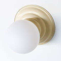Neutral Cream flushmount ceiling light or wall sconce with a frosted white globe.  Stepping back into a bygone era with a touch of modern minimalism, the Abeille Sconce or Flushmount is an artistic blend of form and function. This wall sconce doubles as a flushmount ceiling light, making it a versatile lighting solution for any space. Designed akin to a beehive, its charismatic shape is complemented by curated color options that add a playful element to its retro appeal.