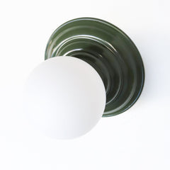 Stepping back into a bygone era with a touch of modern minimalism, the Abeille Sconce or Flushmount in olive green is an artistic blend of form and function. This wall sconce doubles as a flushmount ceiling light, making it a versatile lighting solution for any space. Designed akin to a beehive, its charismatic shape is complemented by curated color options that add a playful element to its retro appeal.