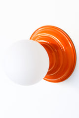 Stepping back into a bygone era with a touch of modern minimalism, the Abeille Sconce or Flushmount  in bright orange is an artistic blend of form and function. This wall sconce doubles as a flushmount ceiling light, making it a versatile lighting solution for any space. Designed akin to a beehive, its charismatic shape is complemented by curated color options that add a playful element to its retro appeal.