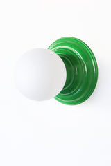 Stepping back into a bygone era with a touch of modern minimalism, the Abeille Sconce or Flushmount in bright green is an artistic blend of form and function. This wall sconce doubles as a flushmount ceiling light, making it a versatile lighting solution for any space. Designed akin to a beehive, its charismatic shape is complemented by curated color options that add a playful element to its retro appeal.