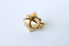 Close-up of a raw brass spike cube knob with a bold, geometric design, featuring four rounded brass spikes on a solid brass cube base.