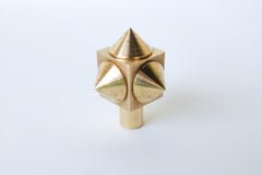 Close-up of a raw brass spike cube knob with a bold, geometric design, featuring four rounded brass spikes on a solid brass cube base.