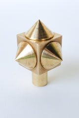 Close-up of a raw brass spike cube knob with a bold, geometric design, featuring four rounded brass spikes on a solid brass cube base.