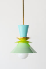 The Astro Pendant light in an airy pastel color scheme, featuring stacked powder-coated metal shades in mint green, lime green, and aqua blue. The fixture’s brass stem and accent plate add warmth, making it a perfect statement piece for contemporary interiors.
