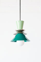 Close-up of the Astro Pendant in Vista Green, Olive Green, and Mermaid Green. This mid-century modern-inspired pendant features a playful combination of colors, with a glossy green top cone, metallic dish accents, and layered conical shades, suspended from a sleek rod.