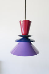 Astro pendant light featuring a bold colorblocked design in Black Cherry, Navy, and Orchid. This sculptural ceiling light is handcrafted with powder-coated metal in a tiered, mid-century modern inspired silhouette. A striking and vibrant choice for kitchens, dining spaces, or eclectic interiors, it brings playful sophistication and a pop of color to maximalist and design-forward homes. Ideal as a single statement piece or grouped over an island.