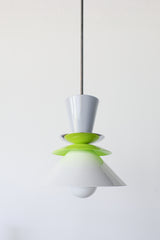 Astro pendant light in a crisp colorblocked palette of grey, chartreuse, and white. This modern ceiling fixture is inspired by mid-century design, featuring stacked powder-coated metal shapes in a sculptural silhouette. The vibrant pop of chartreuse adds playful contrast to the soft neutrals, making it an ideal lighting choice for eclectic, retro, or minimalist kitchens and dining spaces. Designed to stand out, whether used as a single pendant or in a bold row above a kitchen island.