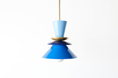 Colorblocked Astro pendant light in hydrangea blue, navy, and Mediterranean blue with a warm brass accent. This sculptural, mid century modern-inspired ceiling fixture adds a bold pop of color to any space. Perfect for eclectic kitchens, creative dining areas, playful living rooms, or vibrant entryways. A statement pendant designed for maximalist interiors, retro-modern homes, or anyone looking to infuse personality and color into their lighting.