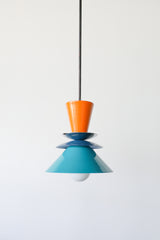 Colorblocked Astro Pendant light featuring bold, powdercoated aluminum shades in vibrant orange peel, rich denim blue, and saturated teal. Accented with a brass detail and suspended from a brass rod. This geometric ceiling light by Sazerac Stitches is handmade in New Orleans and ideal for maximalist, eclectic, or color-forward kitchen designs.