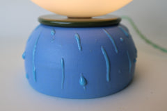 Close-up detail of handmade blue ceramic lamp base with glossy drip glaze accents and olive green rim, showing artisan craftsmanship and modern sculptural design. Perfect for shoppers looking for colorful ceramic lighting or unique handmade table lamps with artistic finishes.
