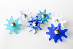 Multiple Splat drawer pulls in various finishes pastel and vibrant blues arranged on a white background, showcasing their versatility and playful character.