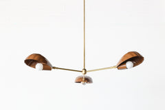 Three-arm Coquille chandelier with fluted shell-inspired light shades in a glossy fudge brown finish, combined with cast brass hardware and a slim ceiling-mounted downrod. This handcrafted chandelier draws from vintage French and Art Deco influences, making it ideal for eclectic interiors, upscale coastal homes, or sunny Mediterranean-style spaces.