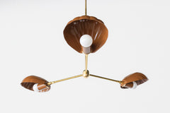 Customizable Art Deco-inspired chandelier featuring sculptural shell shades in rich brown tones, paired with warm brass arms and a center canopy. Designed for coastal and eclectic interiors, this show-stopping lighting piece fits beautifully in Mediterranean villas, breezy European flats, or vintage-modern beach houses with layered textures and warmth.