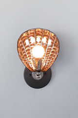 Handmade Coquille Sconce illuminated, showcasing shimmering iridescent ceramic shell in black with glowing copper and purple accents, silver leaf detail, and silver-tone vintage hardware; one-of-a-kind Art Deco-inspired light fixture