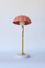 Art Deco-style shell lamp in warm peach with gleaming brass hardware and a round marble base, designed for adjustable task lighting with a vintage flair—blends seamlessly into Nancy Meyers kitchens, coastal living rooms, or chic Parisian apartment decor.