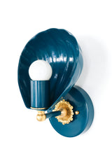Shell-shaped wall sconce with a powdercoated lagoon blue finish and solid brass accents, including a detailed rosette and finial. The sconce features a sculptural shell form that cradles a bulb, casting soft ambient light. Shown from multiple angles on a white background, this coastal-inspired light fixture blends vintage Art Deco design with contemporary elegance, ideal for bedrooms, bathrooms, hallways, and eclectic interiors.