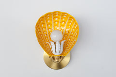 Close-up of hand-painted yellow and orange powdercoated steel wall sconce with white detailing and ornate brass hardware – bold coastal-inspired lighting fixture