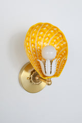 Colorful powdercoated steel Coquille sconce with orange, yellow, and white painted scallop-shaped shade and brass backplate – modern handmade wall light for eclectic interiors
