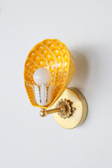 Side view of scalloped powdercoated steel Coquille sconce in yellow, orange, and white on white wall – retro-inspired custom lighting with brass foliate socket