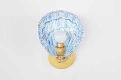 Scalloped white and blue wall sconce with hand-painted brushstroke detailing on a powder-coated steel shell-shaped shade, attached to a solid brass round wall plate with floral rosette and decorative socket. The crisp white background emphasizes the vibrant cobalt strokes and detailed craftsmanship, ideal for showcasing this one-of-a-kind artisan sconce as a bold lighting statement for bathrooms, hallways, or bedrooms.
