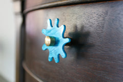 tiffany blue pearl splat knob with brass details on a dark wood nightstand