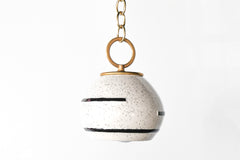 Neutral cream and black speckled geometric pendant lamp with oversized brass loop on brass chain.  Boho style modern Pendant light that can be swagged.