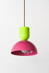 Close-up of the Taeuber Pendant in neon chartreuse and bright doll pink by Sazerac Stitches, featuring a glossy two-tone powder-coated finish and brass downrod. This sculptural pendant light showcases minimalist curves and handcrafted detailing, blending midcentury modern design with a soft, neutral palette. Perfect for kitchens, dining rooms, or entryways, this artisan-made fixture adds a timeless and elegant touch to both contemporary and classic interiors.