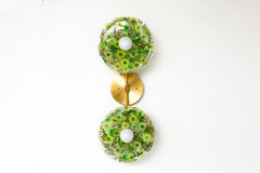 Modern two light wall sconce with brass hardware and purple flowers. Features resin-encapsulated green flowers with greenery, ferns, and leaves.  Adds a real-like nature theme to any interior design project.  Called the Botanico Sconce by Sazerac Stitches. Features green flowers with greenery