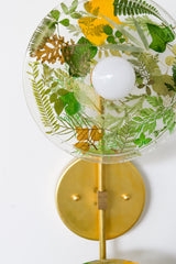 Modern two light wall sconce with brass hardware. Features resin-encapsulated greenery, ferns, and leaves.  Adds a real-like nature theme to any interior design project.  Called the Botanico Sconce by Sazerac Stitches. Features green and yellow leaves & greenery