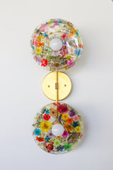 Encapsulated Floral two light wall sconce with flowers in every color flowers and greenery.  Unique wall light with real florals and greenery.  Adds a botanical and nature theme to lighting. Botanico sconce by Sazerac Stitches. multi-colored floral wall sconce light fixture.