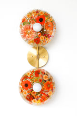 Encapsulated Floral two light wall sconce with orange flowers and greenery.  Unique wall light with real florals and greenery.  Adds a botanical and nature theme to lighting. Botanico sconce by Sazerac Stitches. Orange floral wall sconce light fixture