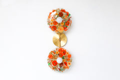 Encapsulated Floral two light wall sconce with orange flowers and greenery.  Unique wall light with real florals and greenery.  Adds a botanical and nature theme to lighting. Botanico sconce by Sazerac Stitches. Orange floral wall sconce light fixture