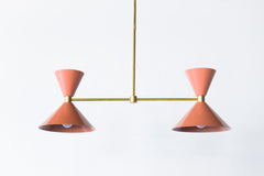 Two Light Linear Chandelier in peach and brass.  Midcentury modern style cone shape.  Perfect over long dining tables, a kitchen island, and narrow spaces.  Adds a pop of peach fuzz Pantone color of the year to any decor style.