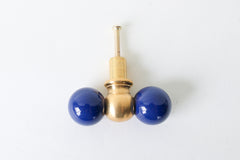 The Double Gumball drawer pull in navy blue and brass adds a bold, sculptural touch to furniture and cabinetry. This oversized modern knob is handcrafted in New Orleans and features glossy powder-coated navy blue spheres flanking a solid raw brass center. Its playful silhouette makes it perfect for eclectic and maximalist interiors, kids’ spaces, or statement-making dressers. The raw brass naturally patinas over time, offering warmth and character to any room. Ideal for non-kitchen uses like large drawers,