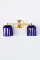 Double Marcella Sconce by Sazerac Stitches featuring two bold cobalt blue glazed ceramic shades paired with a solid brass fixture. Handmade in the USA, this sculptural Art Deco-inspired wall sconce brings a striking pop of color to bathrooms, hallways, or bedrooms while offering functional, compact lighting.