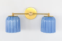 Front view of Marcella Double Sconce in glazed sky blue ceramic with fluted ribbed shades and round brass backplate, modern handcrafted wall sconce for eclectic, traditional, or transitional interiors