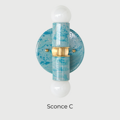 The Thalia Sconce in Teal and Grey Marbled finish is a bold, artistic wall light with two globe bulbs and a circular brass base. Featuring hand-applied marbled enamel in coastal-inspired hues, this sconce is perfect for adding a unique touch to bathroom lighting, powder rooms, or hall spaces.