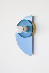 Color-drenched Kin Sconce in celestial blue and hydrangea with a cream socket and brass backplate, ideal for monochromatic bedroom wall lighting or bold hallway installations. A perfect fit for eclectic design lovers seeking playful, sculptural lighting with a modern silhouette and saturated color palette.
