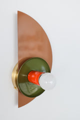 Contemporary geometric light fixture with stacked shapes in a warm fall-inspired palette of fudge brown, olive green, and flame orange, perfect for eclectic or midcentury interiors.