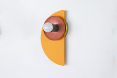 The Kin Sconce in mustard, peach, and olive—featuring layered, high-contrast powder-coated steel shapes and a globe bulb. A vibrant choice for creative spaces, kids’ rooms, powder rooms, or hallways with modern, postmodern, or geometric decor vibes.