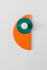 With its zesty orange backplate, jewel-toned mermaid green disc, and creamy neutral socket, this Kin Sconce is a compact sculpture of warm-cool color harmony. The dramatic silhouette and contrasting tones give off strong Bauhaus and postmodern vibes, making it an artful addition to kids' rooms, creative studios, or design-forward bathrooms.