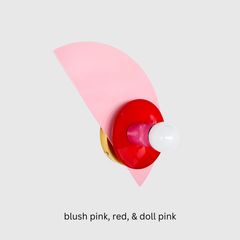 Color-blocked Kin Sconce in blush pink, bold red, and doll pink with brass hardware, photographed on a white wall; perfect for eclectic, maximalist interiors seeking playful wall lighting with a modern pop of color—ideal for kids’ rooms, color-drenched bedrooms, or vibrant hallways.