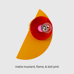 The Kin Sconce in mustard, Flame, & Doll Pink packs a punch. With its clean half-moon silhouette and saturated colors, this fixture turns any wall into a statement moment. Works beautifully in maximalist, retro, or color-forward spaces.