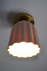 Close-up of the Marcella Flushmount ceiling light with an unglazed porcelain ceramic shade and brass canopy. This handmade flush mount features Art Deco-inspired fluted curves and sculptural detailing, perfect for bathrooms, hallways, and elegant low-ceiling spaces. The soft white finish adds a timeless, neutral look ideal for minimal and maximalist interiors alike.