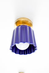 Marcella flushmount light fixture in glazed cobalt blue ceramic with a fluted Art Deco-inspired shape and warm brass canopy. A sculptural, handmade ceiling light perfect for hallways, powder rooms, or color-drenched interiors. Elegant blue ceramic flush mount with vintage charm.