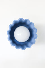 Close-up of the Marcella Flushmount ceiling light featuring a handmade, unglazed soft blue ceramic shade and brushed brass canopy. This sculptural Art Deco-inspired flush mount is ideal for modern hallways, bedrooms, or powder rooms needing a pop of color.