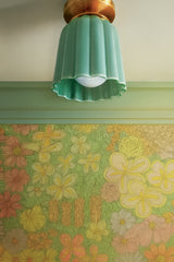 Jade green Marcella flushmount ceiling light by Sazerac Stitches, installed against green crown molding and vibrant floral wallpaper. The celadon-style glaze enhances its ridged ceramic design, making it a feminine Art Deco-inspired accent that complements playful Chinoiserie interiors. Perfect compact light for hallways, entryways, or powder rooms.