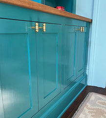 Customer-installed Milne Knobs in solid brass shown on vibrant teal painted cabinetry with oak countertop. The three-piece curvy brass cabinet knobs add a bold yet refined detail to the custom cabinetry, blending classic craftsmanship with a modern pop of color. This stylish hardware choice elevates the eclectic, maximalist look of the space while offering functionality and visual interest. Ideal for kitchens, built-ins, or statement storage units, the Milne Knob is available in all brass or a mixed brass a